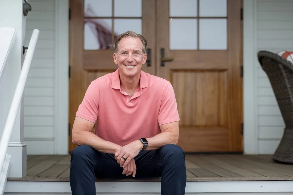 Mark Zides, smiling, seated on a porch step.